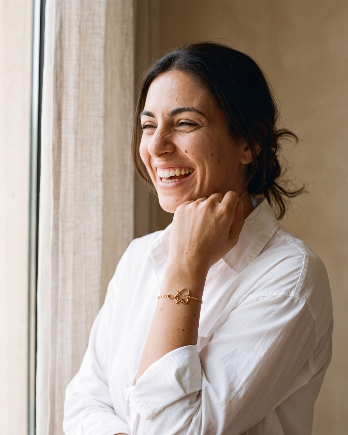 Smiling woman wearing The Faithful Script bracelet in gold [c:gold]