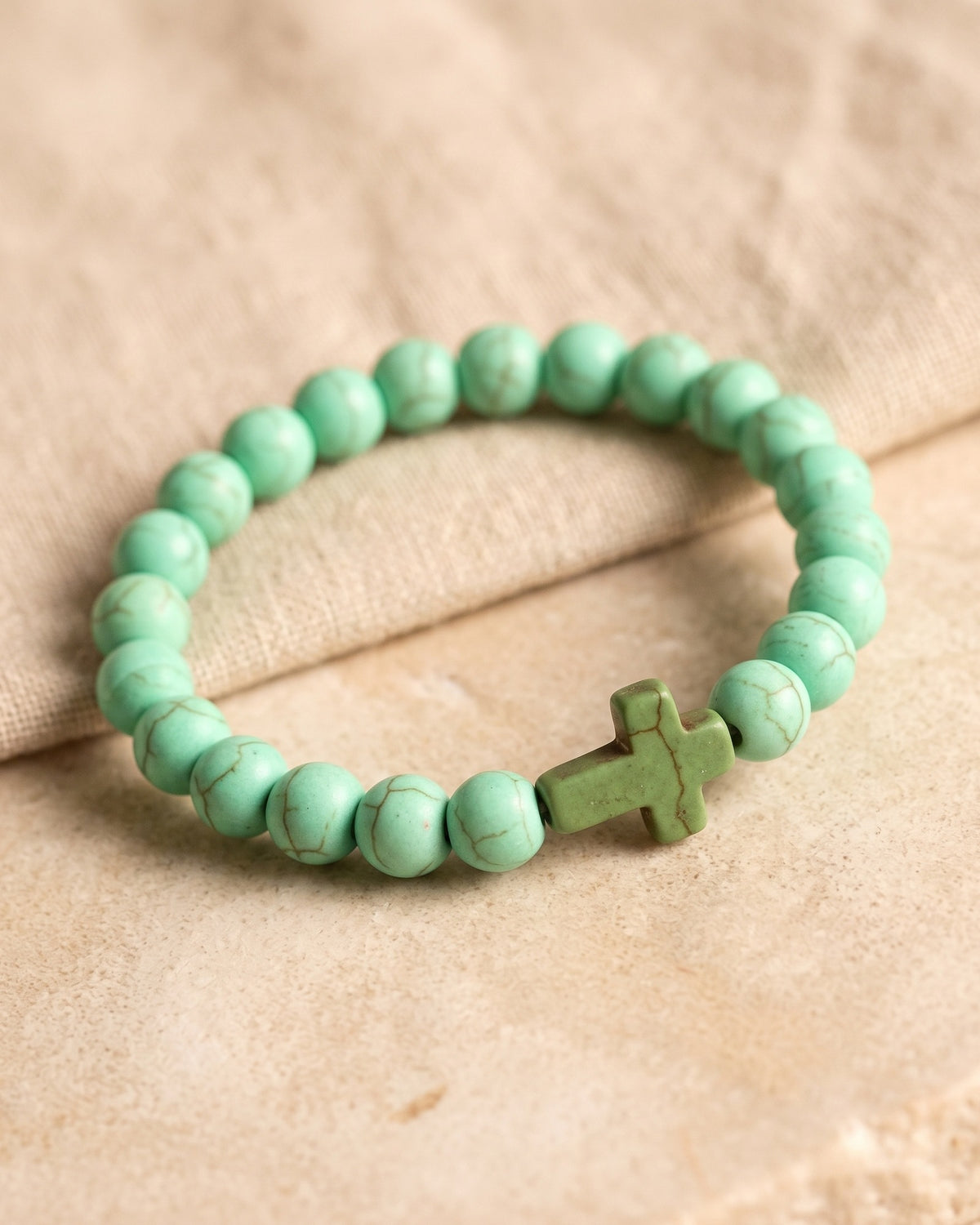 Close-up of the green Beaded Cross bracelet, three-quarter view [c:green]