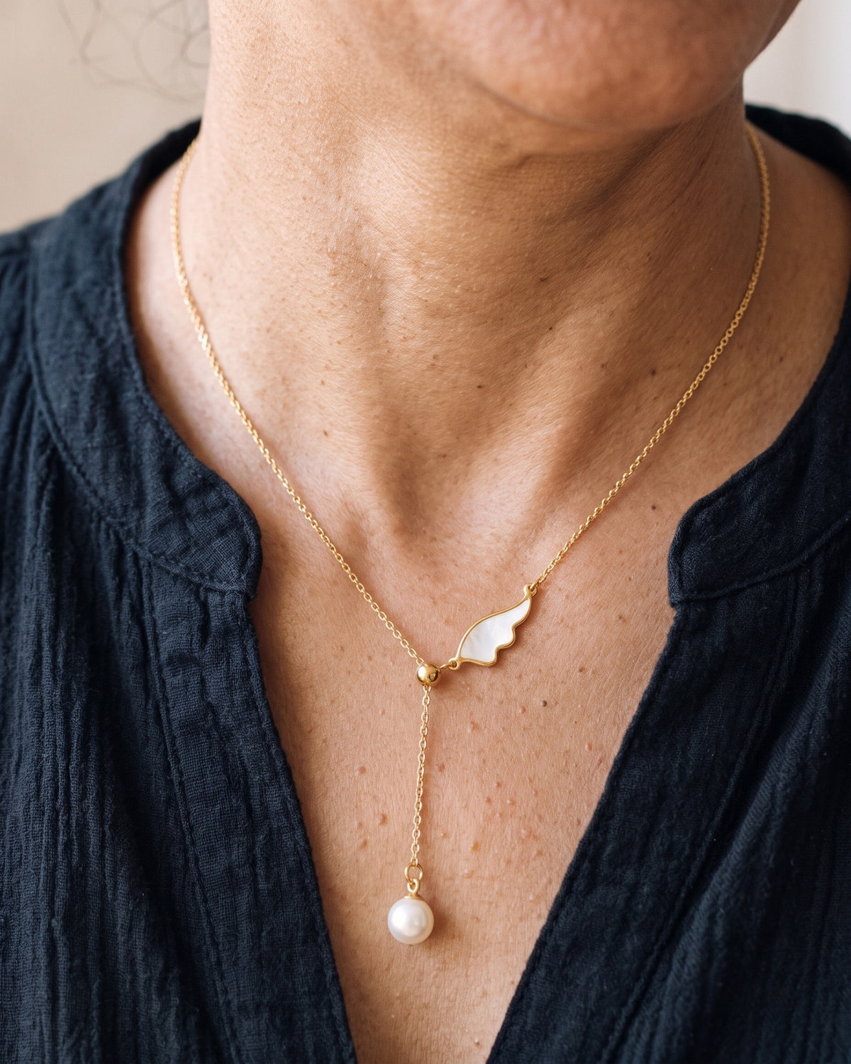 The gold Angelic Pearl worn by a woman, close-up, true to size