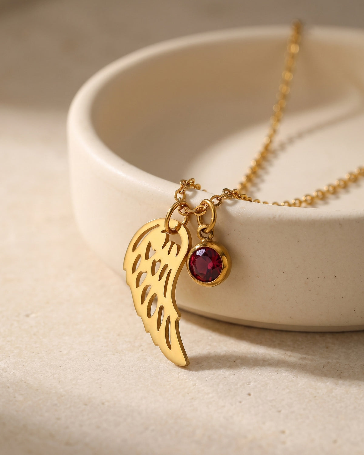 The Angelic Birthstone necklace draped on a ceramic dish [c:january]