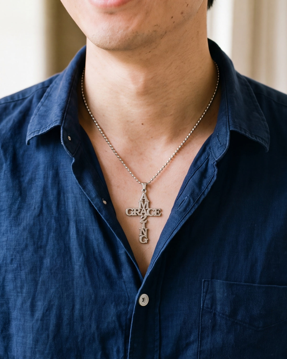 The Amazing Grace cross worn by a man, close-up from chin to chest, true to size