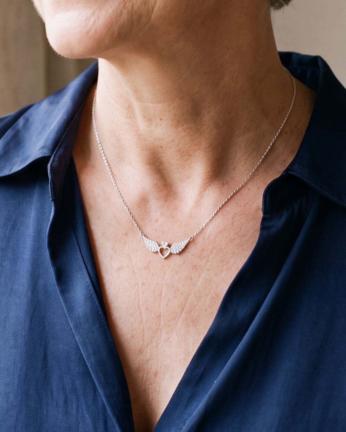 The Angelic Heart worn by a woman, close-up from chin to chest, true to size [c:silver]