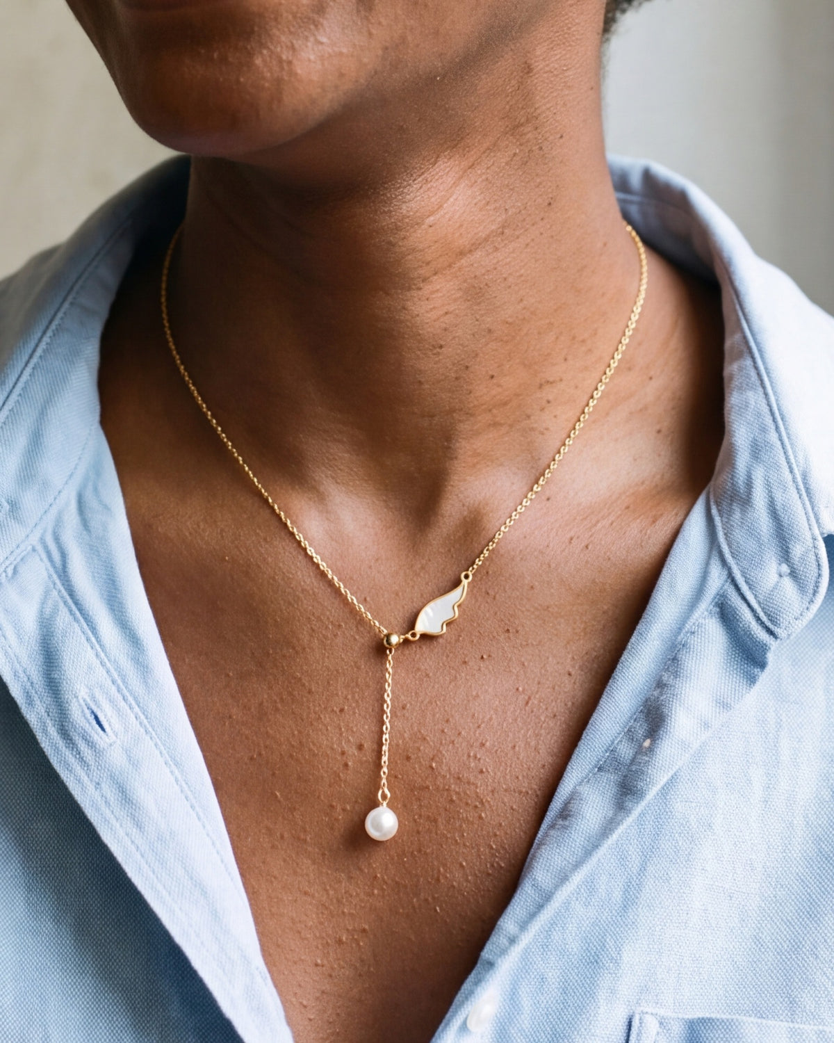 The gold Angelic Pearl worn by a woman, close-up from chin to chest, true to size