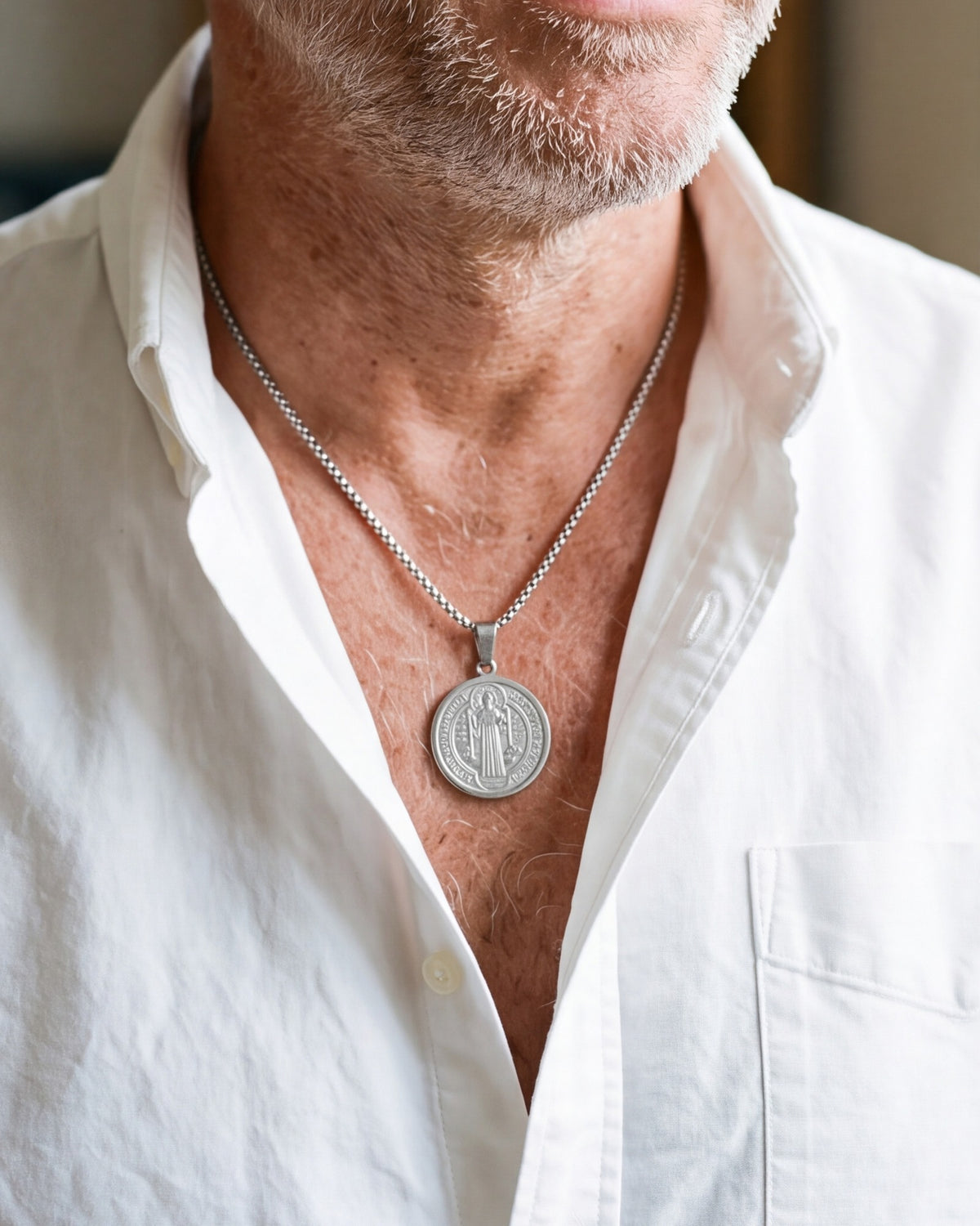 The silver Benedictine Medal worn by a man with a white shirt, close-up, true to size [c:silver]