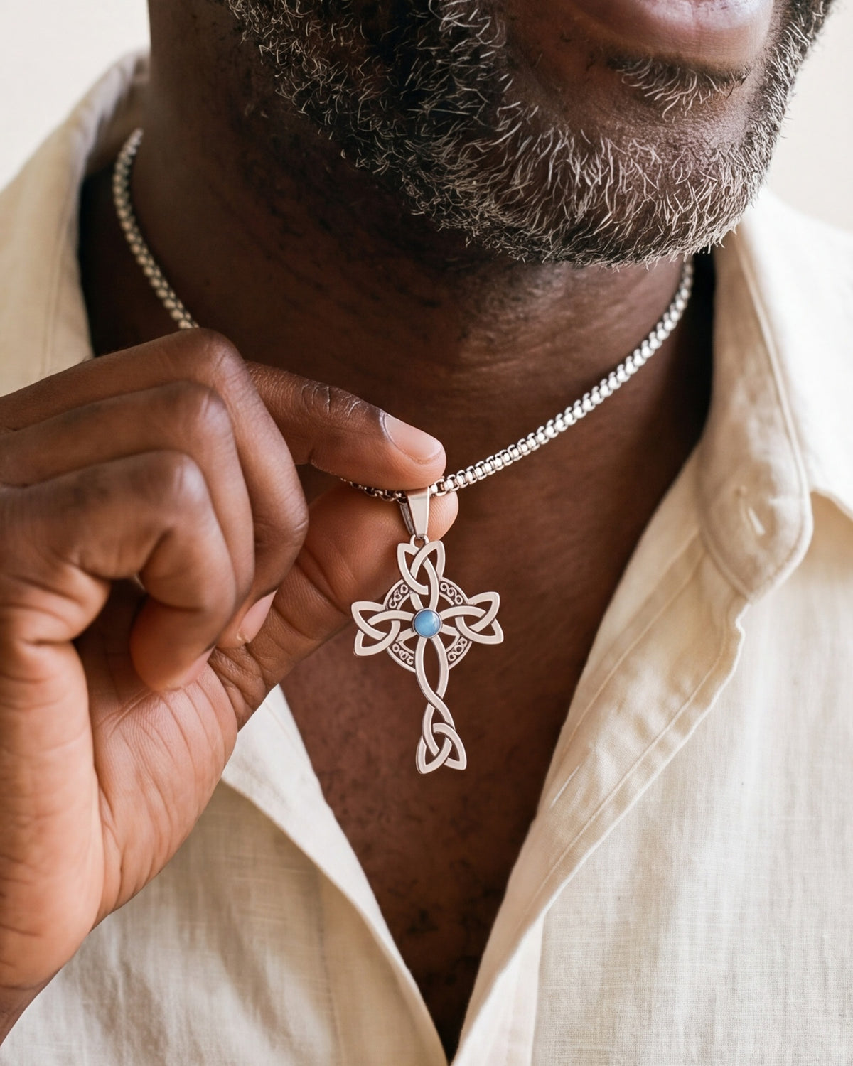 The silver Celtic Knot Cross held between the fingers, true to size [c:silver]