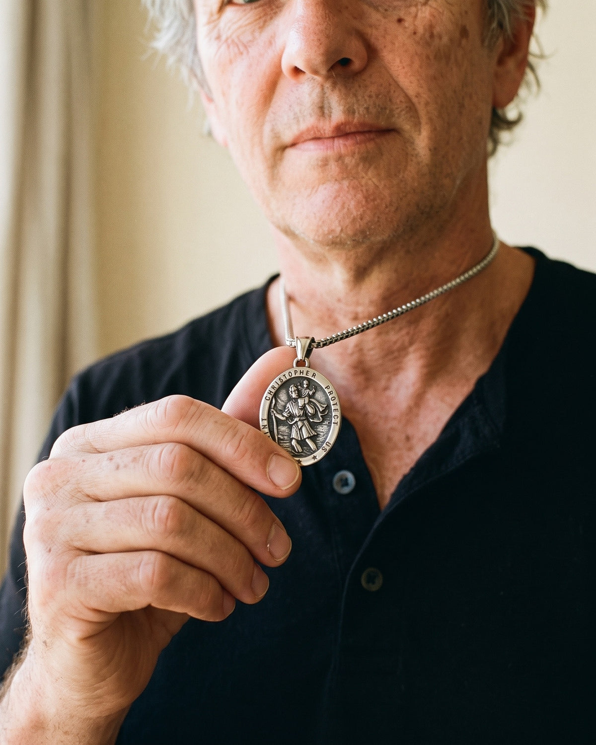 Man holding The Christopher Crossing between the fingers