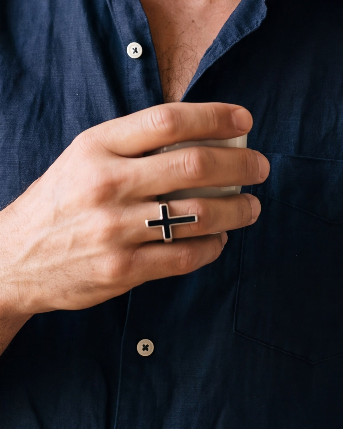 The silver Darkened Cross worn by a man, close-up, true to size
