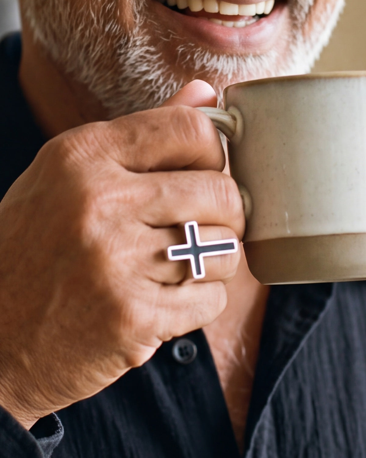 The silver Darkened Cross worn by a man, close-up on the hand, true to size