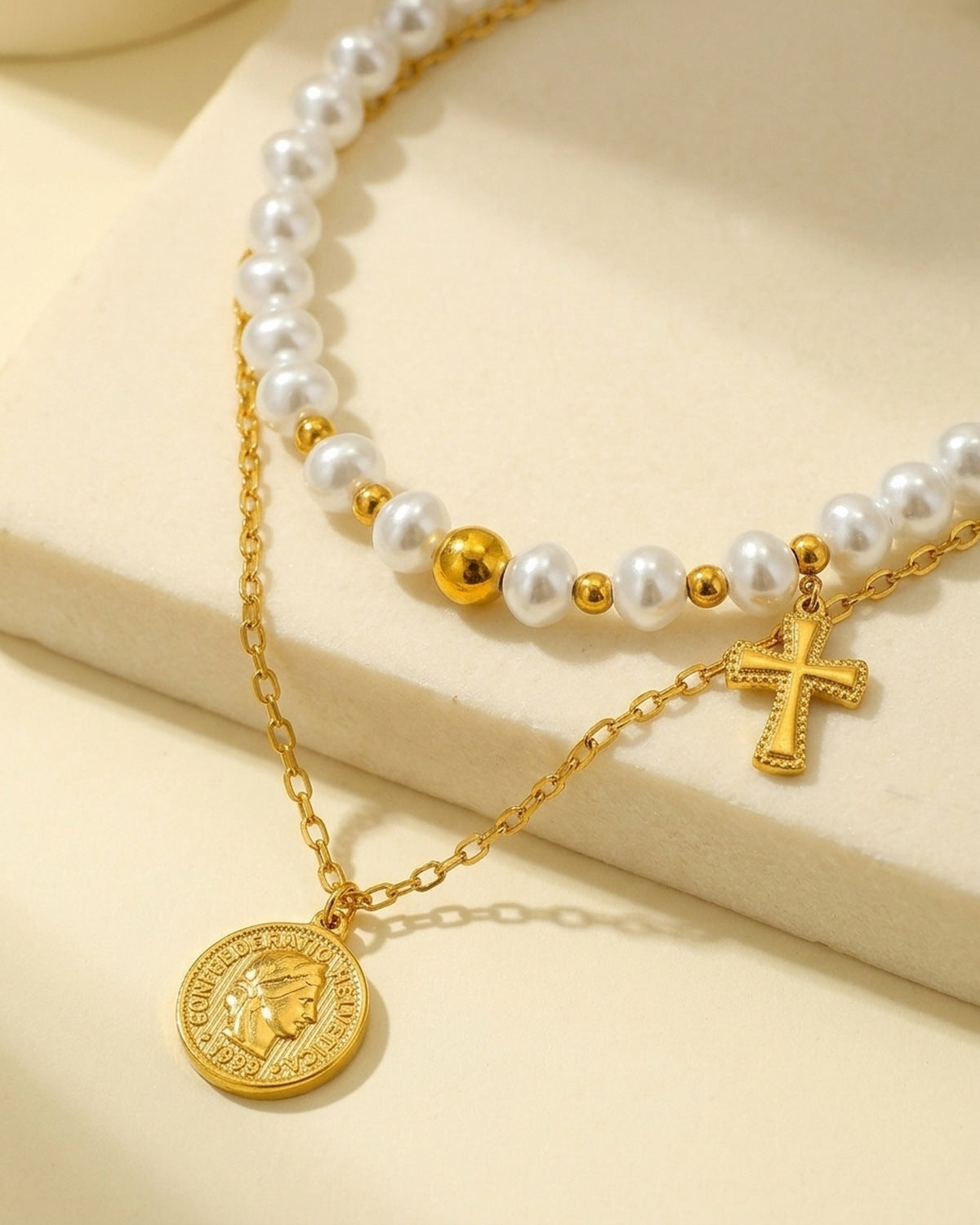 Close-up of The Devout Layers: pearl choker, cross charm and coin medal