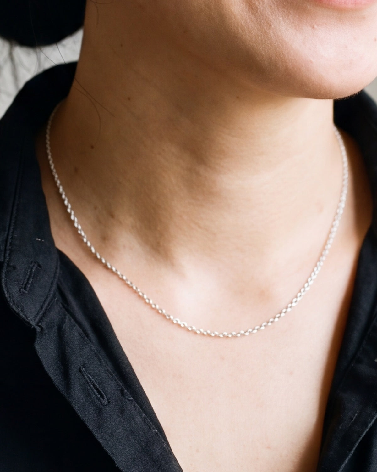 The silver Enduring Chains worn by a woman, close-up from chin to chest, true to size