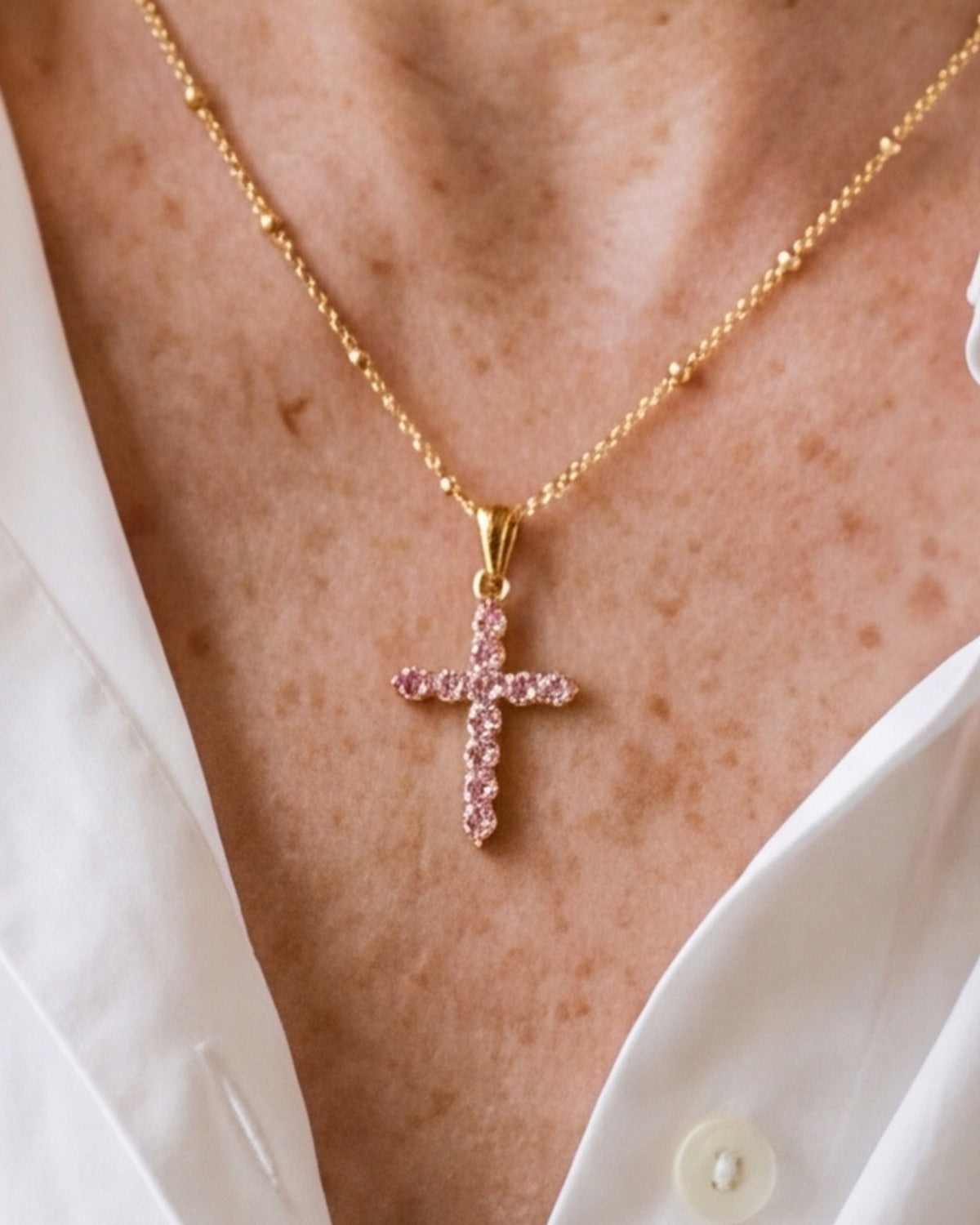 The Gemmed Cross worn by a woman, close-up, true to size [c:gold-pink]