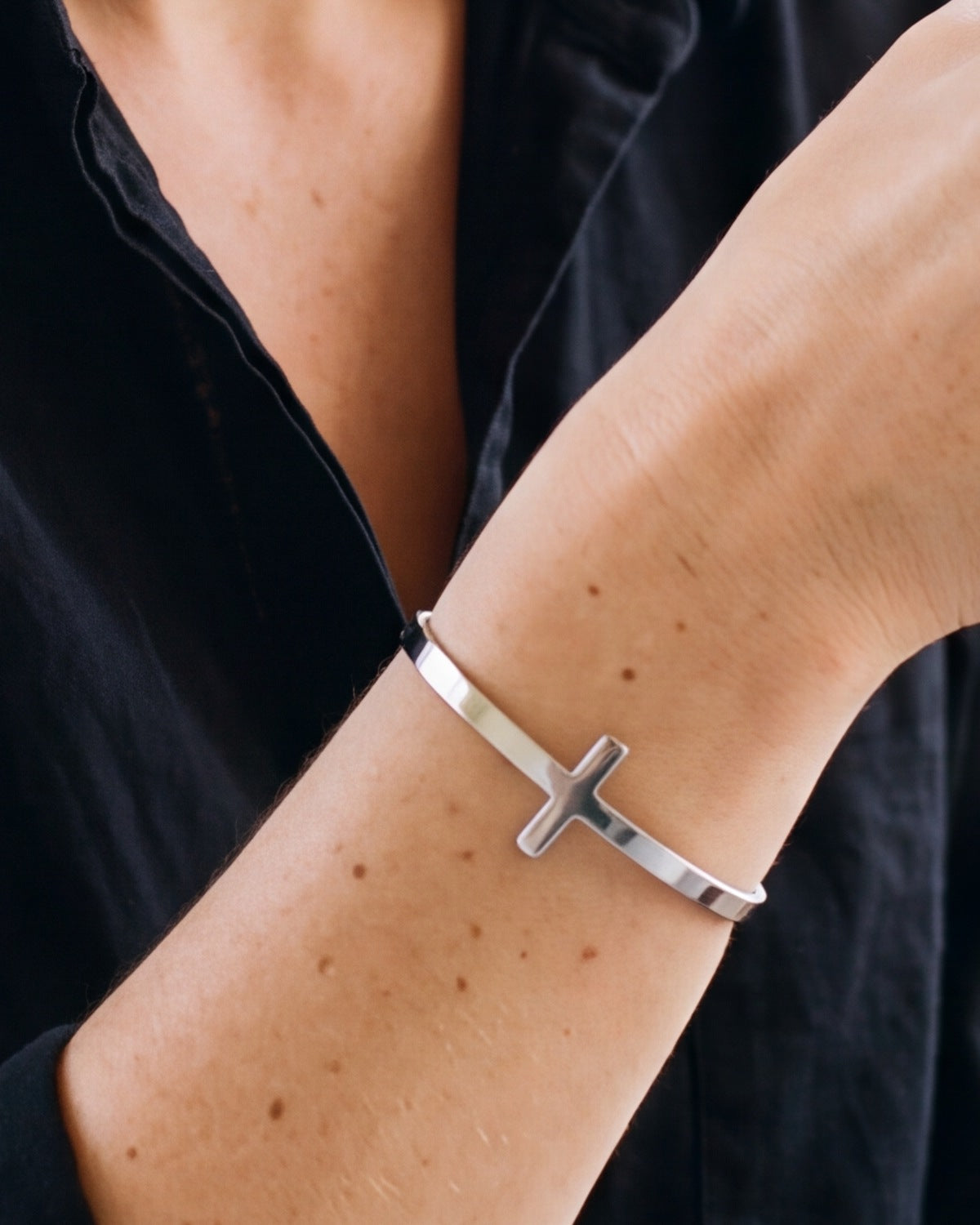The silver Gentle Cross on a woman's wrist, close-up, true to size [c:silver]
