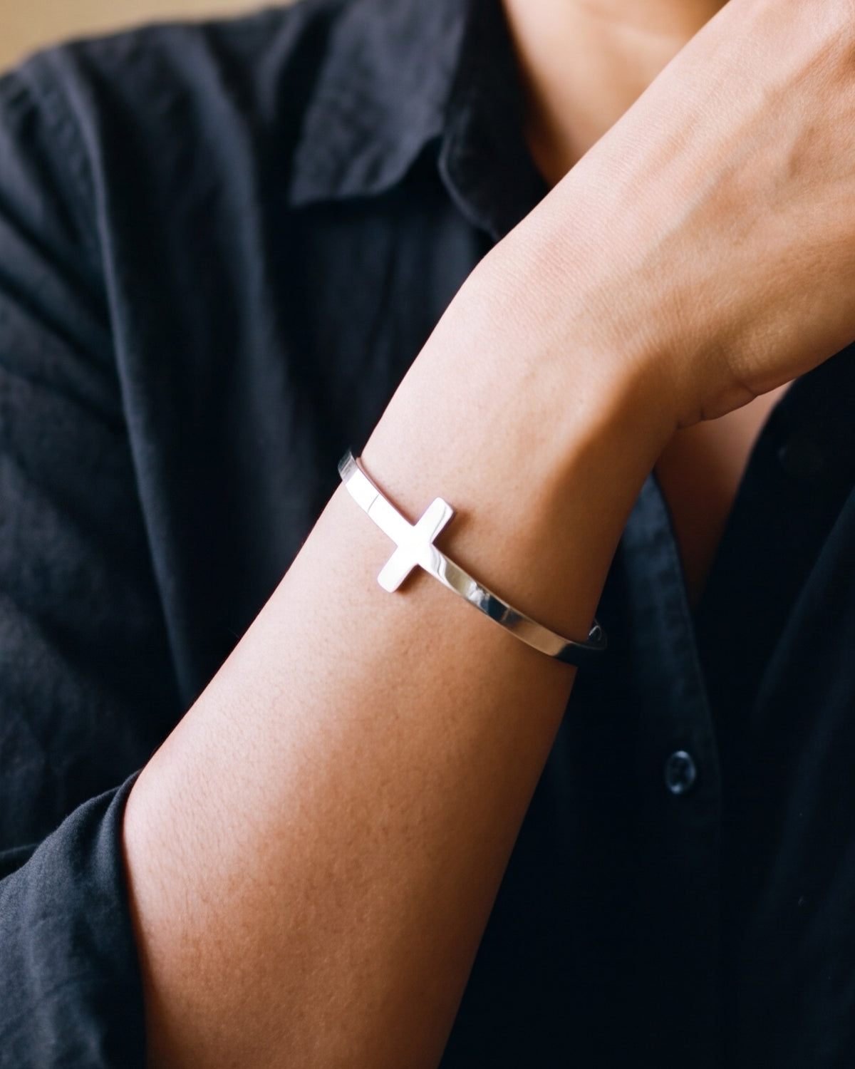 The silver Gentle Cross worn by a woman, close-up on the wrist, true to size [c:silver]
