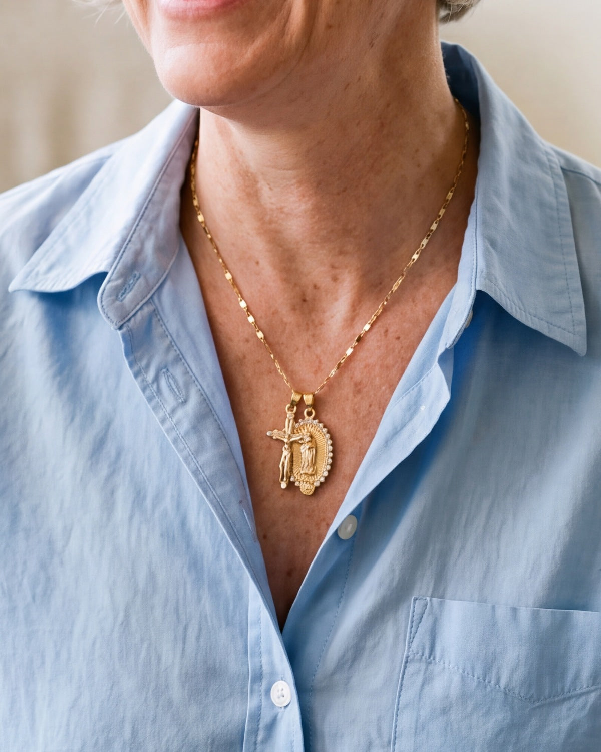 The gold Guadalupe Crucifix worn by a woman, close-up, true to size [c:gold]