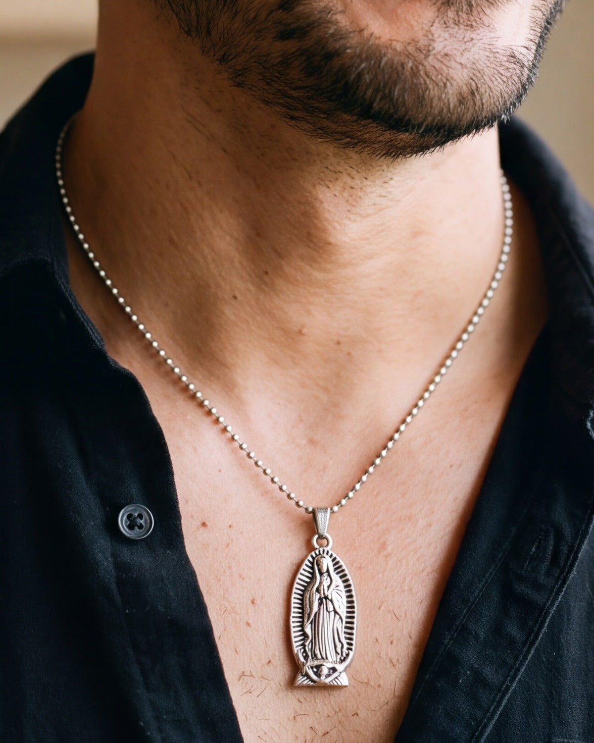 The silver Guadalupe Relief worn by a man, close-up from chin to chest, true to size