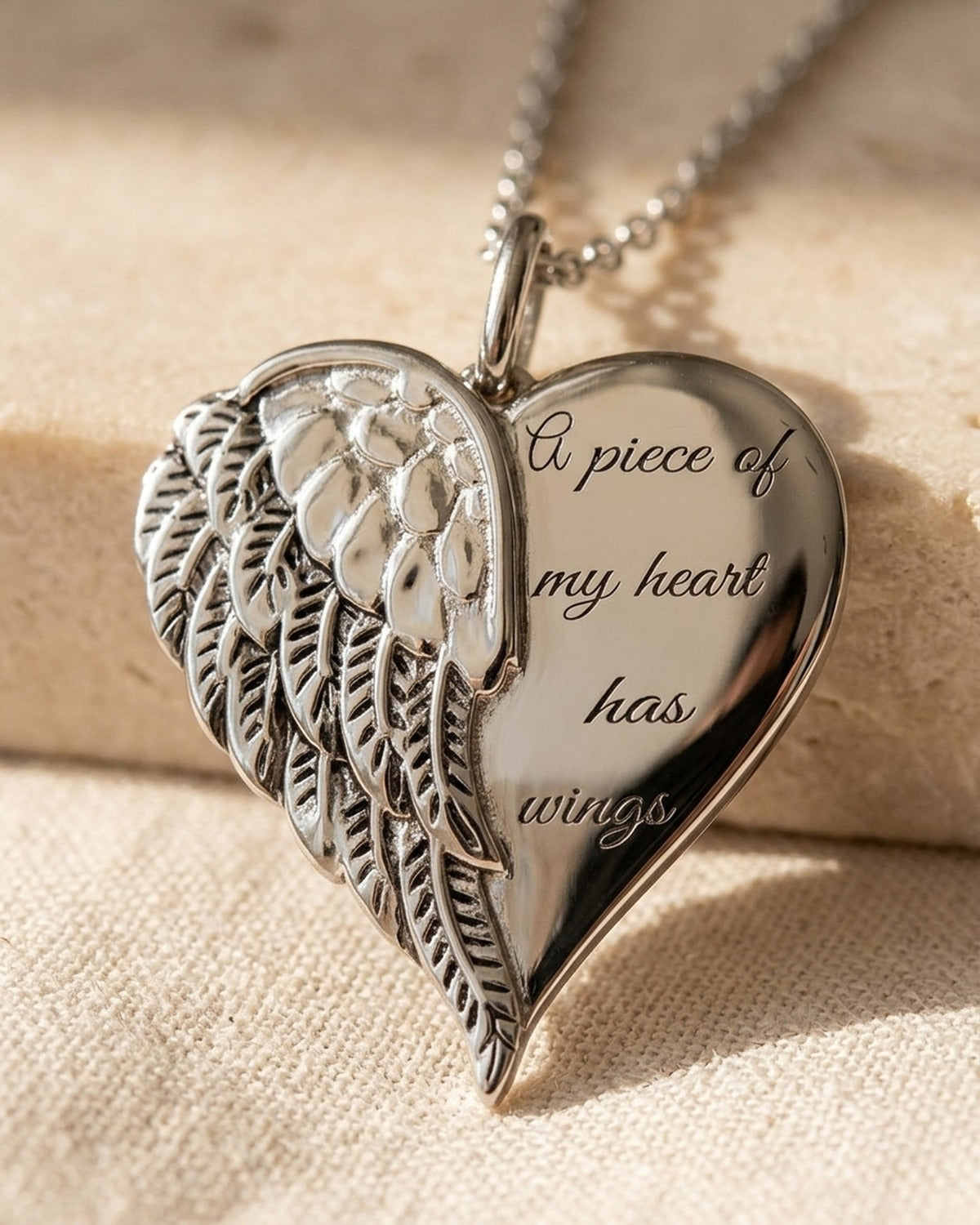 Close-up of The Heart with Wings pendant, engraved text [c:silver]