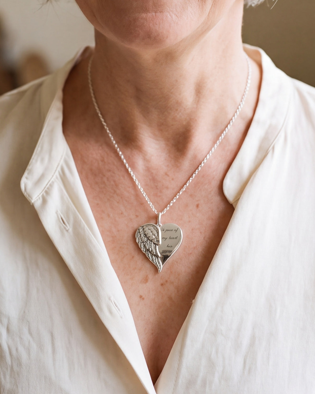 The Heart with Wings necklace worn, second close-up, true to size [c:silver]
