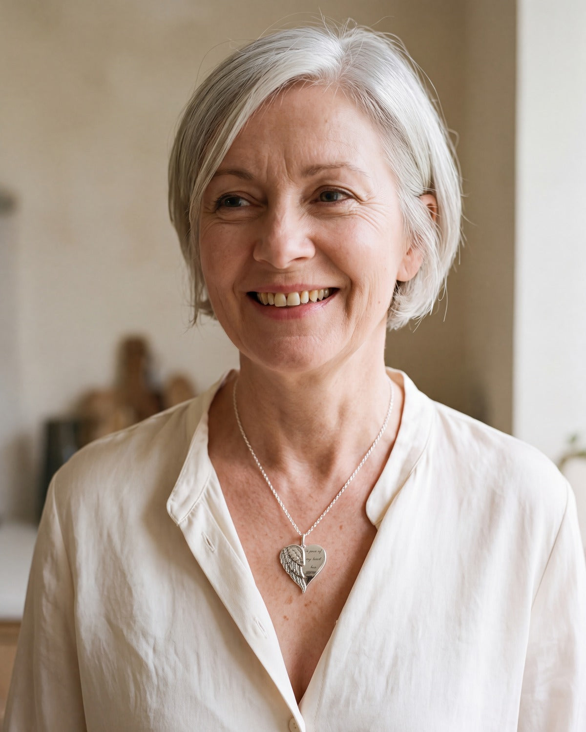 Smiling woman wearing The Heart with Wings necklace [c:silver]