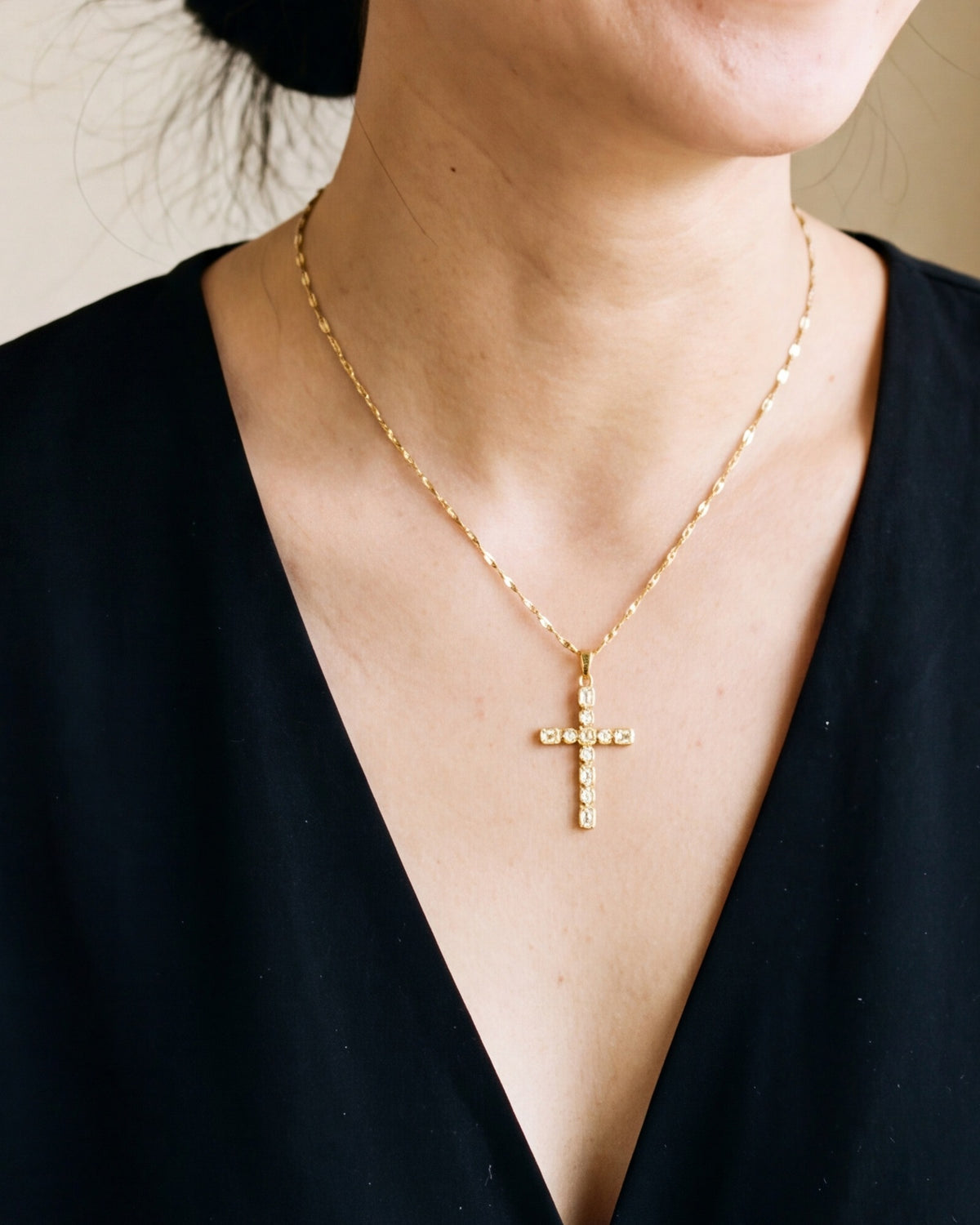 The gold Jeweled Cross worn by a woman, close-up from chin to chest, true to size