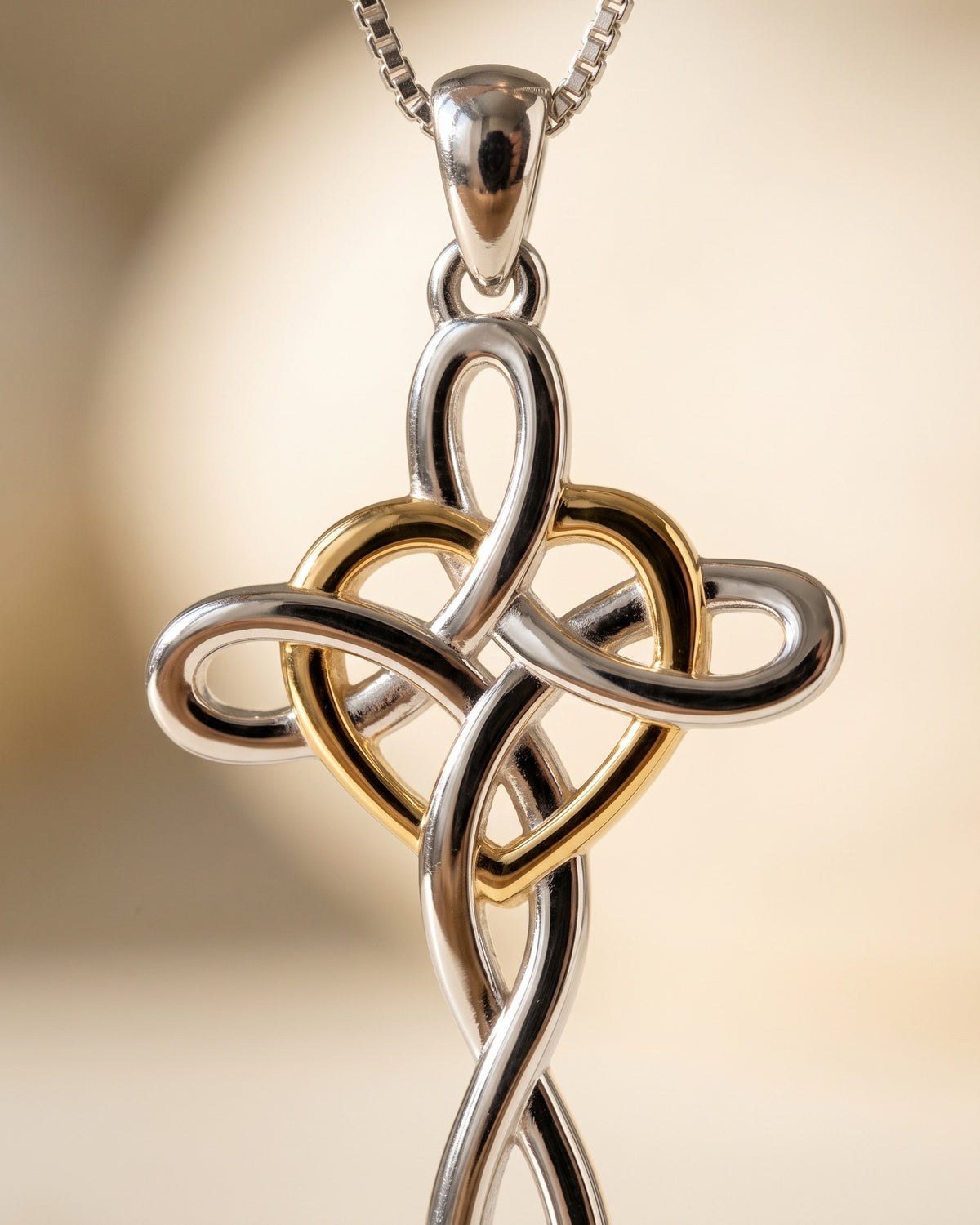 Macro detail of The Knotted Heart Cross, gold heart woven through the silver knot