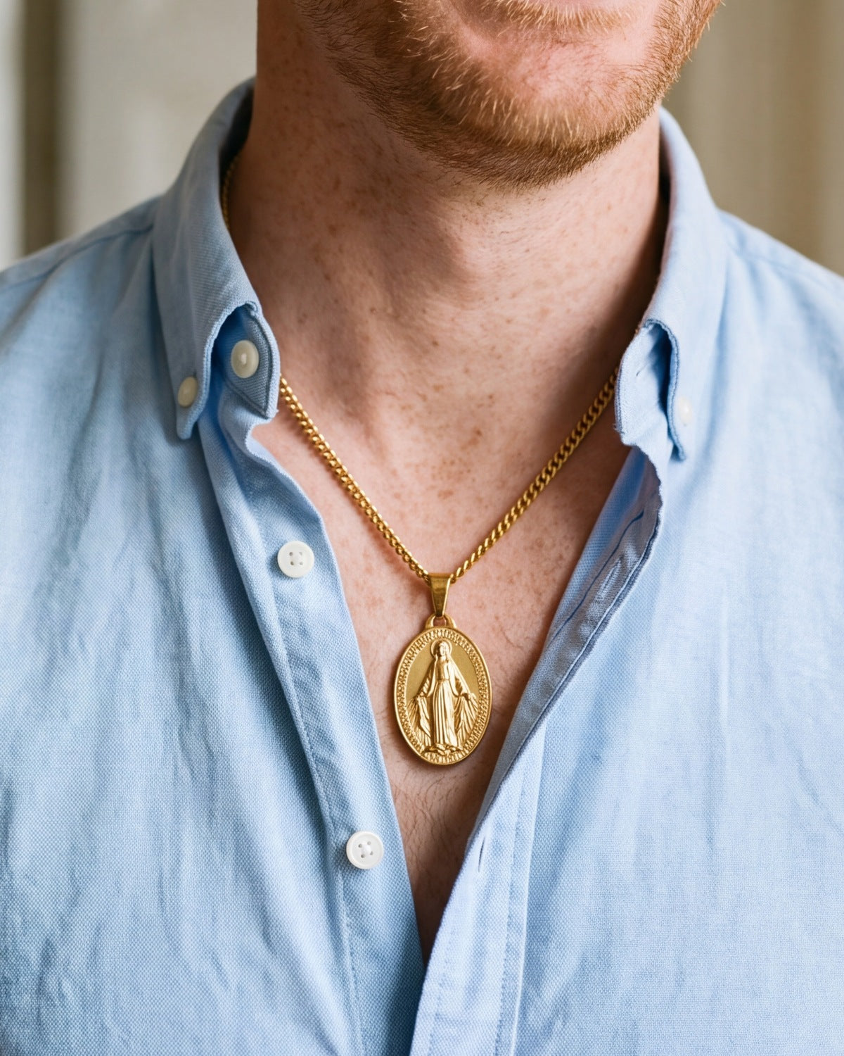 The gold Miraculous Medal worn by a man, close-up, true to size
