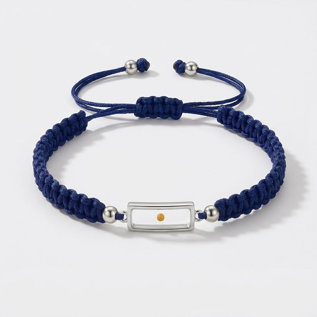 Packshot of The Mustard Seed Bracelet: navy braided cord, silver-tone frame holding a real mustard seed