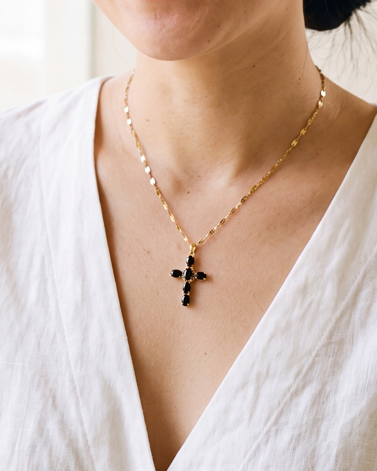The gold Obsidian Cross worn by a woman, close-up from chin to chest, true to size [c:gold]