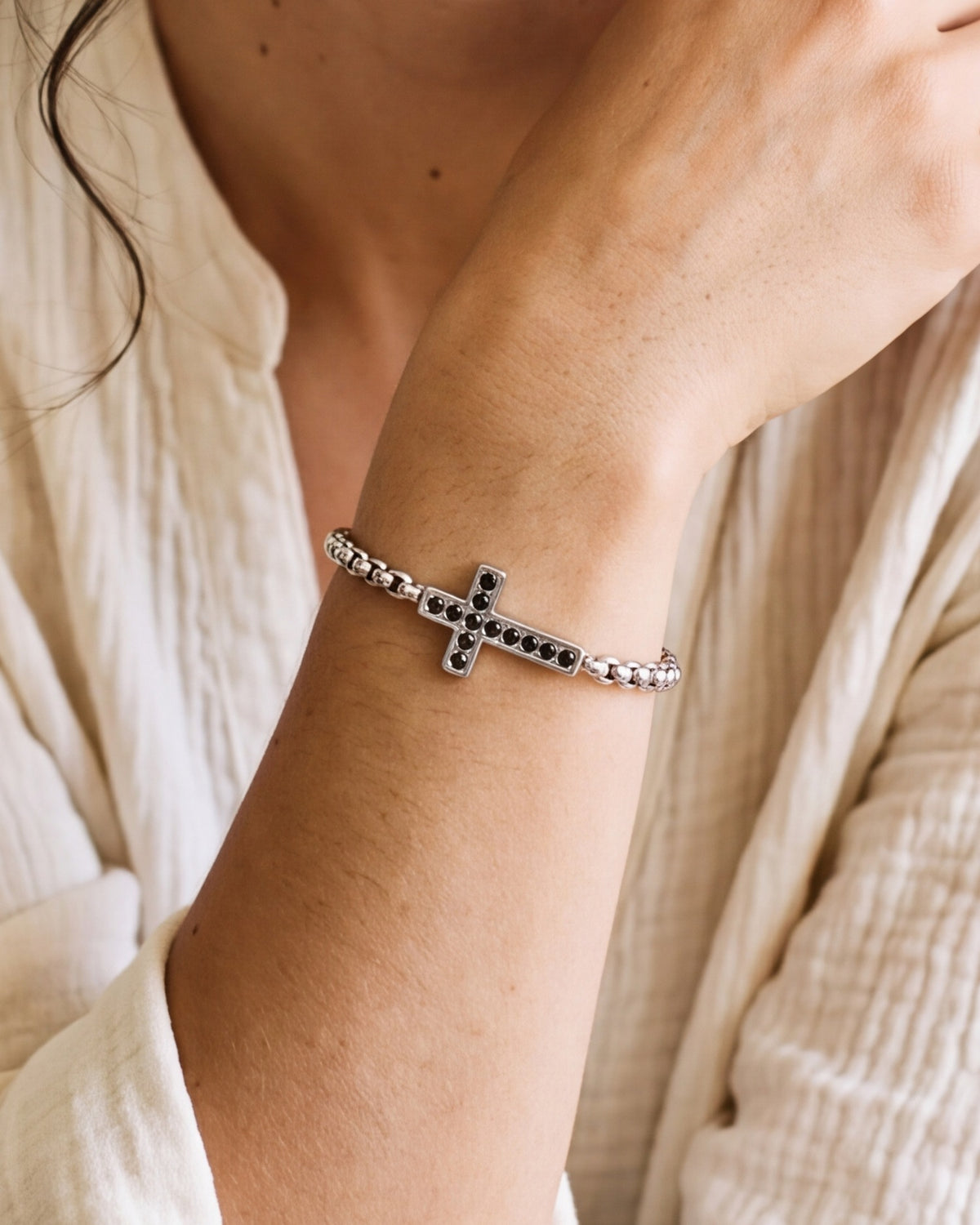 The silver Onyx Cross worn by a woman, close-up, true to size
