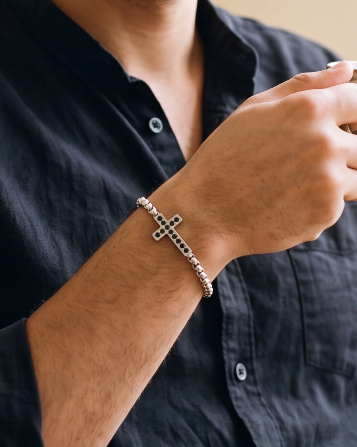 The silver Onyx Cross worn by a man, close-up on the wrist, true to size