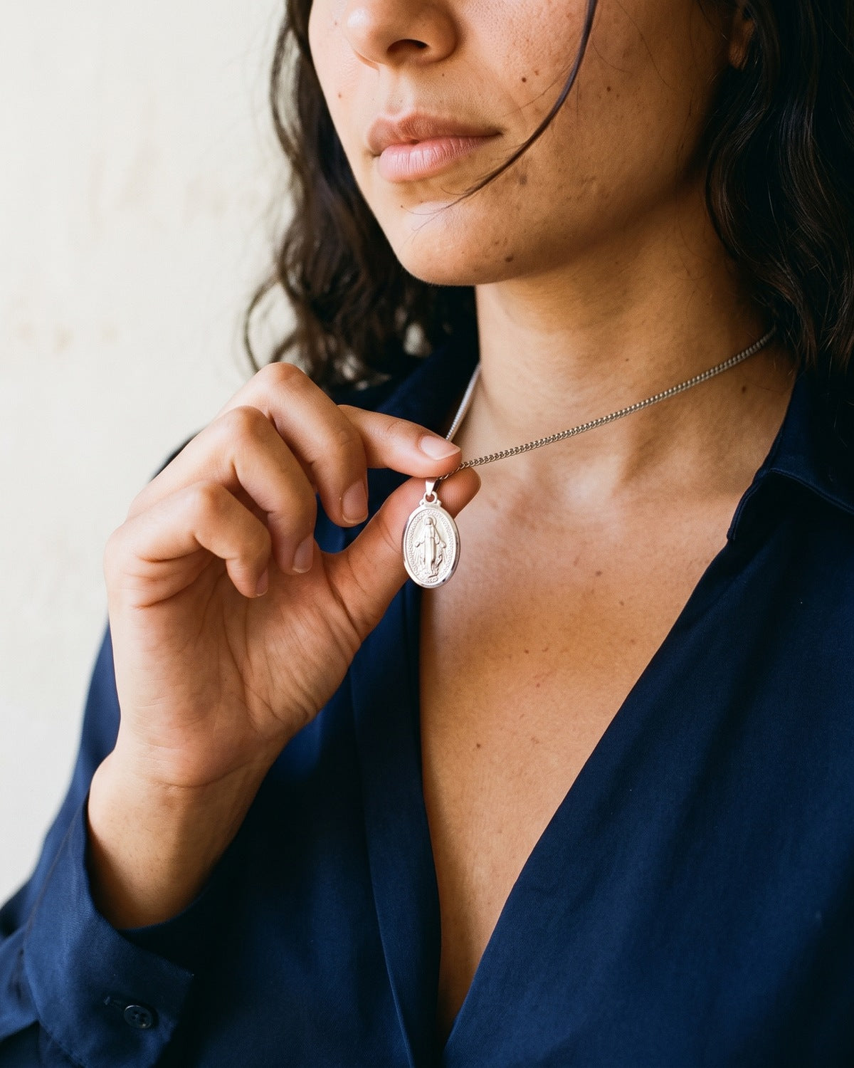 Woman holding The Petite Miraculous Medal between the fingers [c:silver]