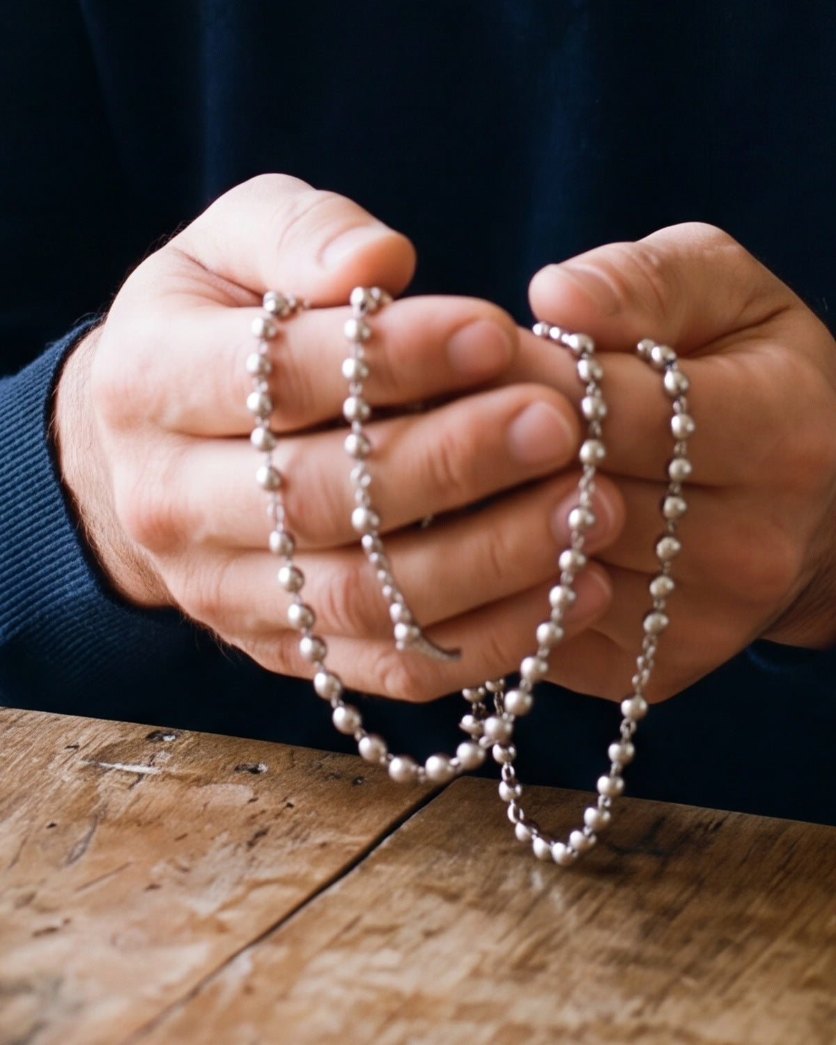 The silver Prayerful Journey held in a man's hands, close-up, true to size [c:silver]