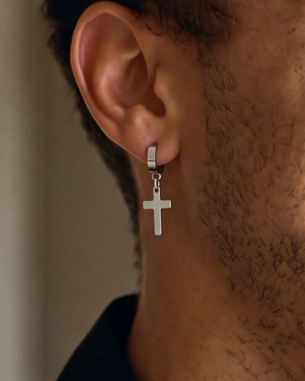 The Radiant Cross earring worn by a man, second ear close-up, true to size [c:silver]