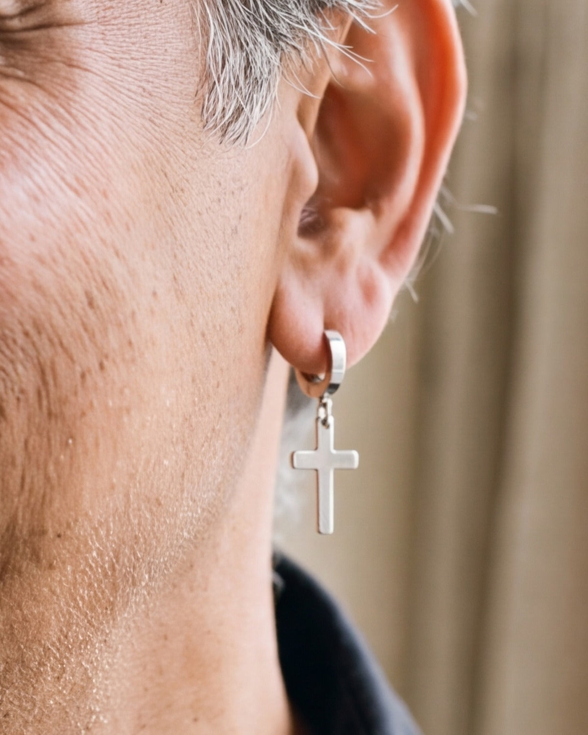 The Radiant Cross earring worn by a man, close-up, true to size [c:silver]