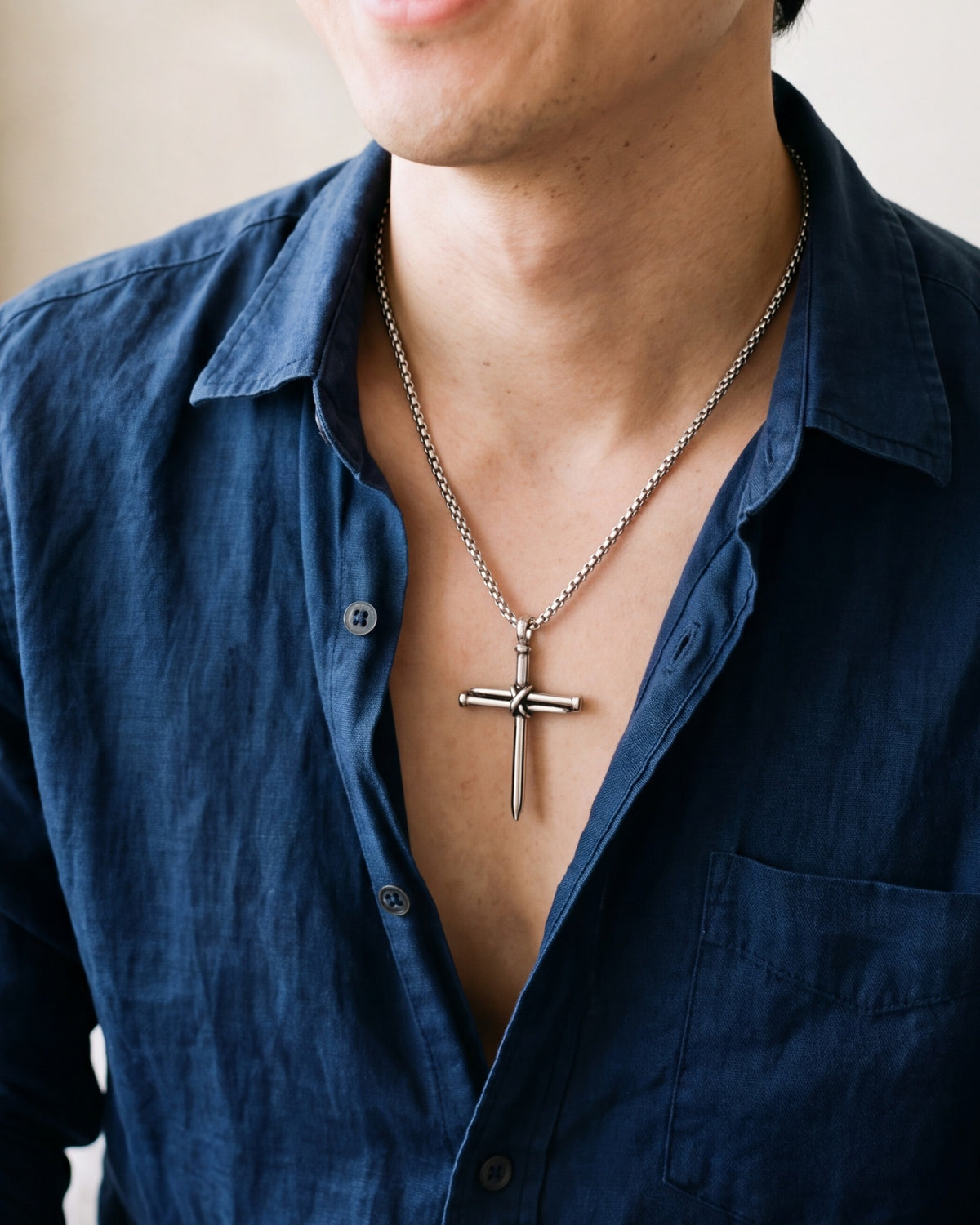 The Reverent Nails cross worn by a man, close-up from chin to chest, true to size [c:silver]