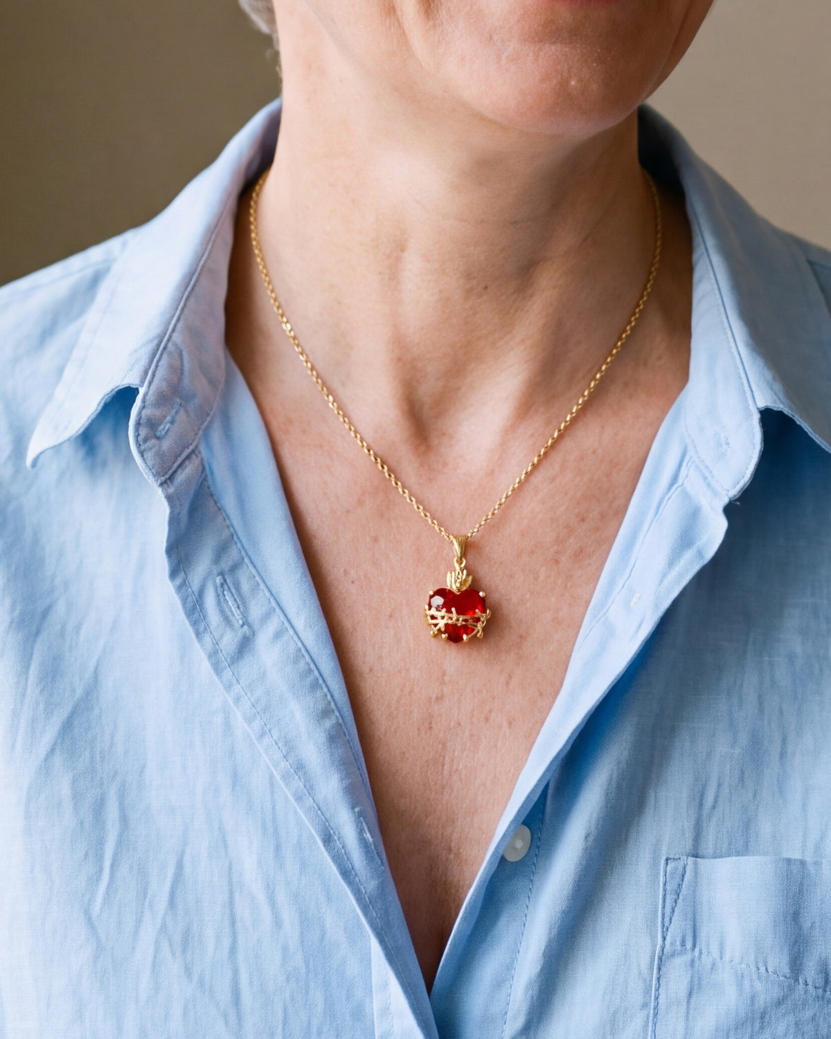 The gold Sacred Heart Flame worn by a woman, close-up, true to size [c:gold]