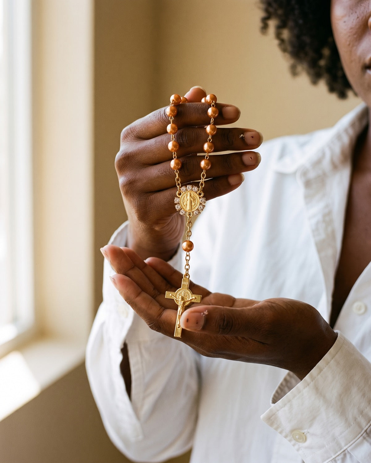 The orange Saint Benedict Decade held in the hands, true to size [c:orange]