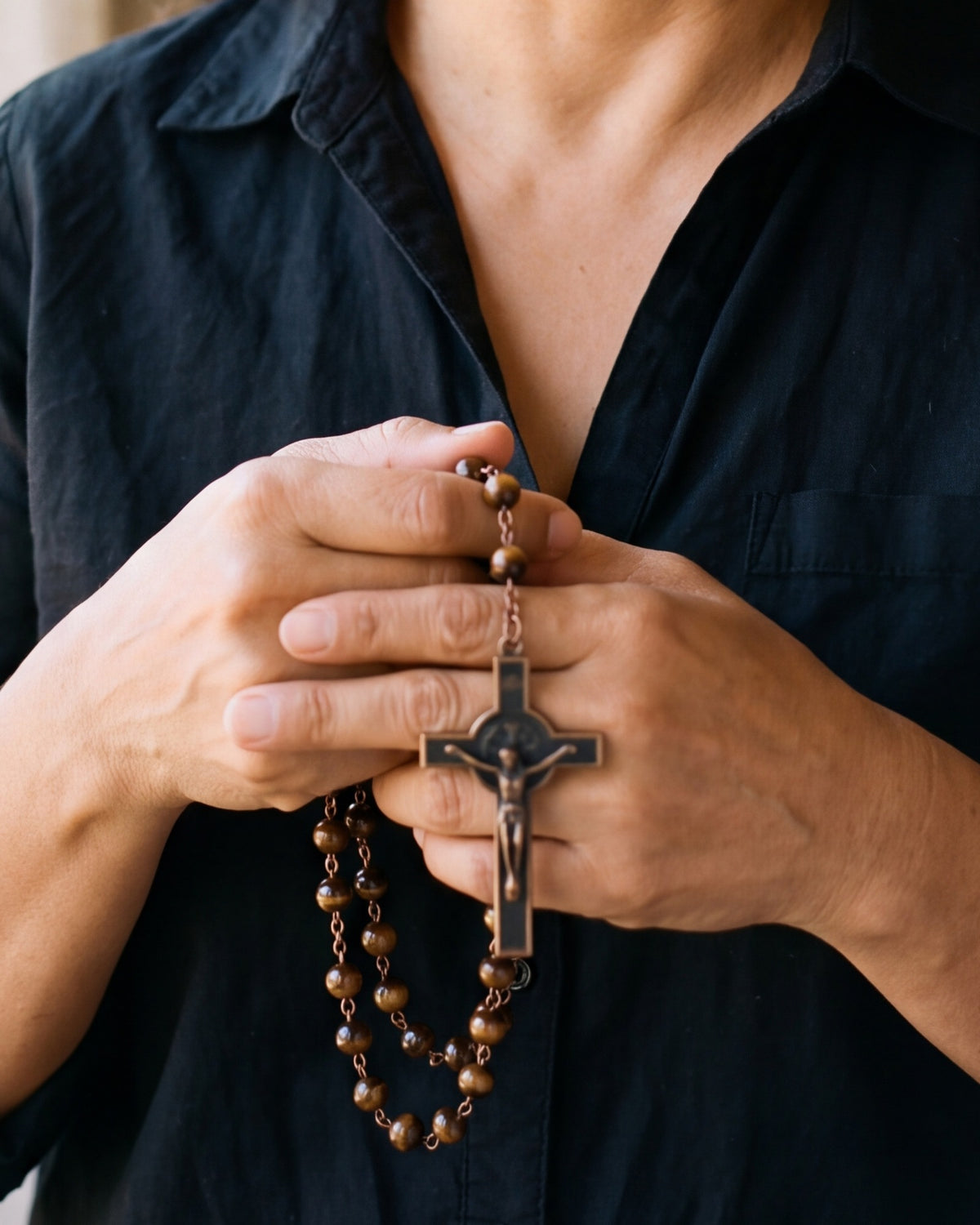 The Saint Benedict Rosary held in both hands, close-up