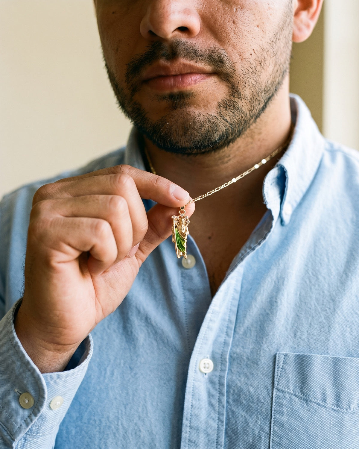 Man holding The Saint Jude Necklace between the fingers