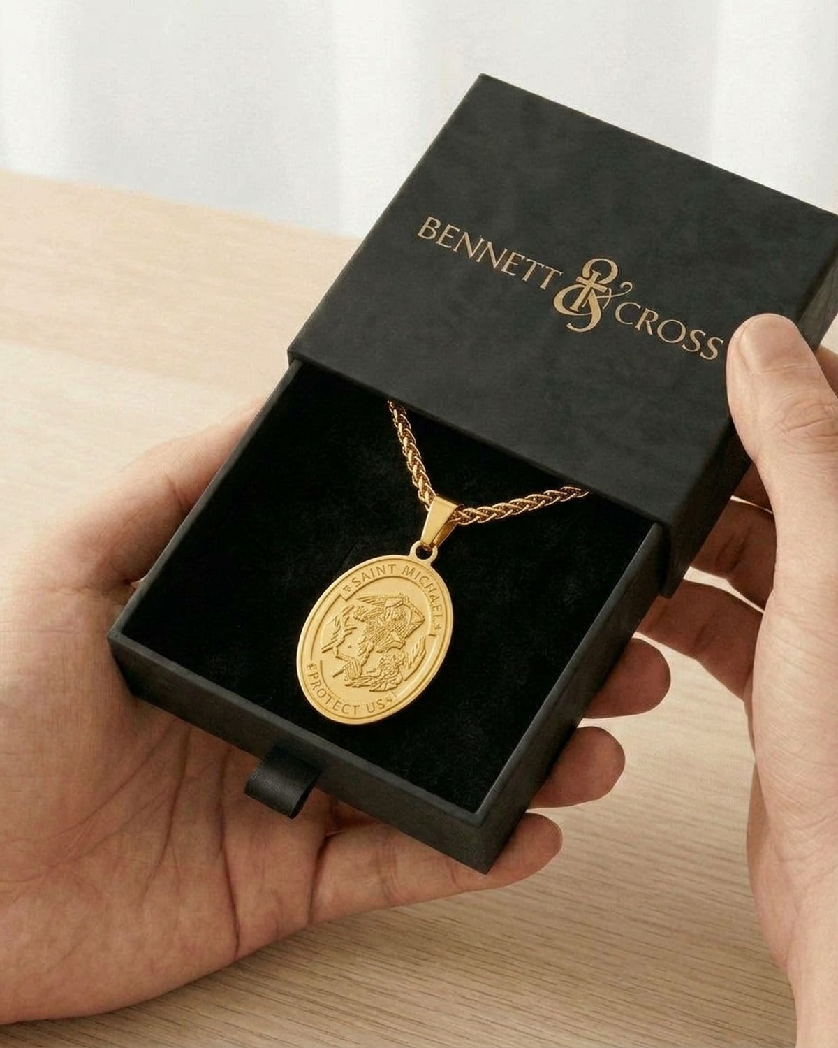 The gold Saint Michael Medal in its black Bennett & Cross gift box