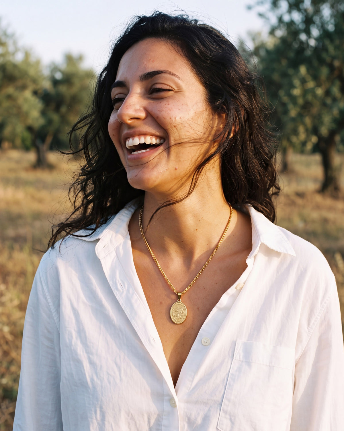 Smiling woman wearing the gold Saint Michael Medal with a white shirt [c:gold]