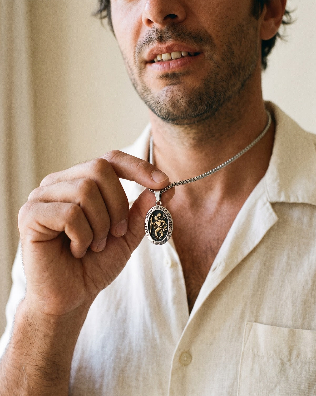 Man holding The Voyager's Protector Saint Christopher medal between his fingers