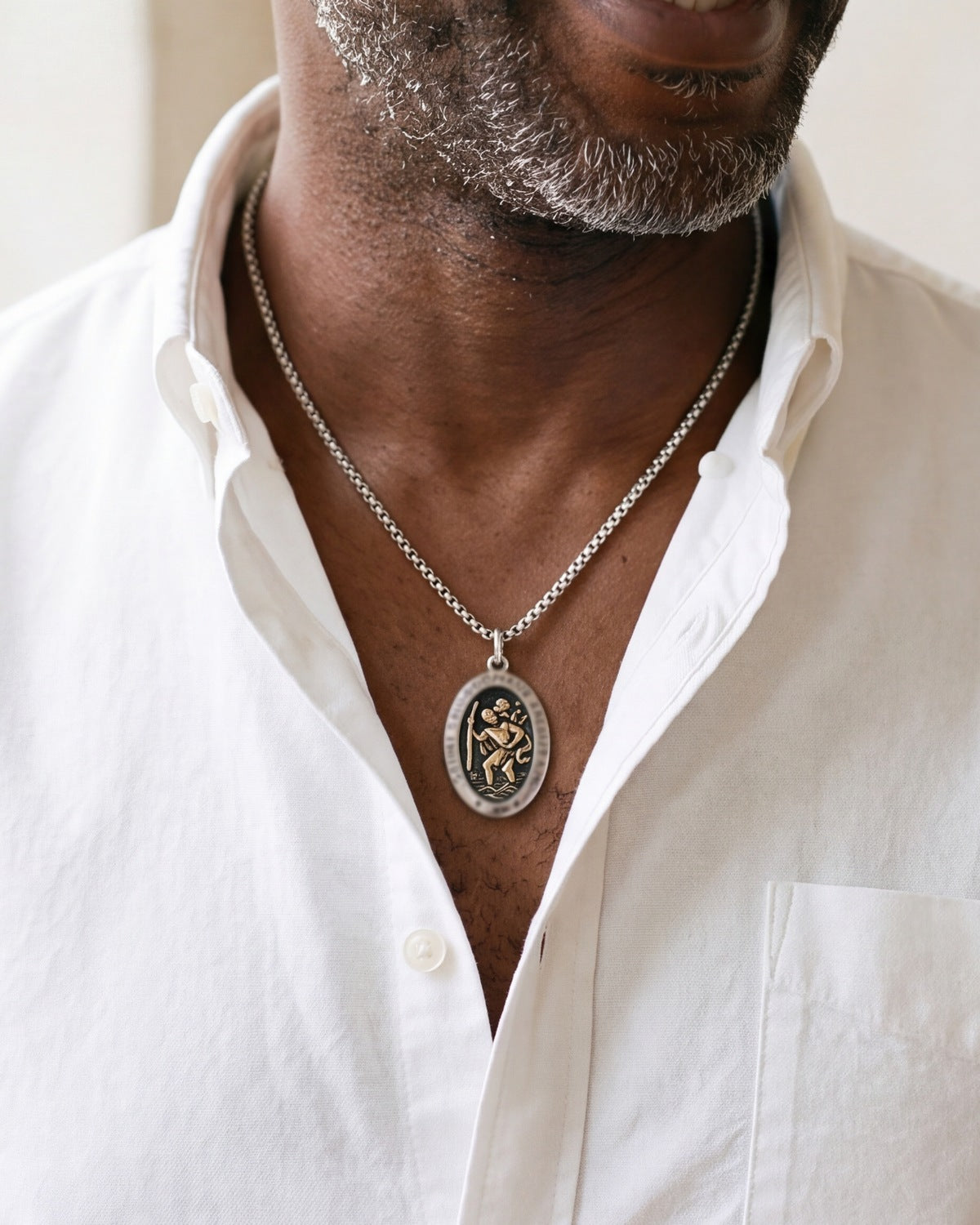 The Voyager's Protector Saint Christopher medal worn by a man, close-up from chin to chest, true to size